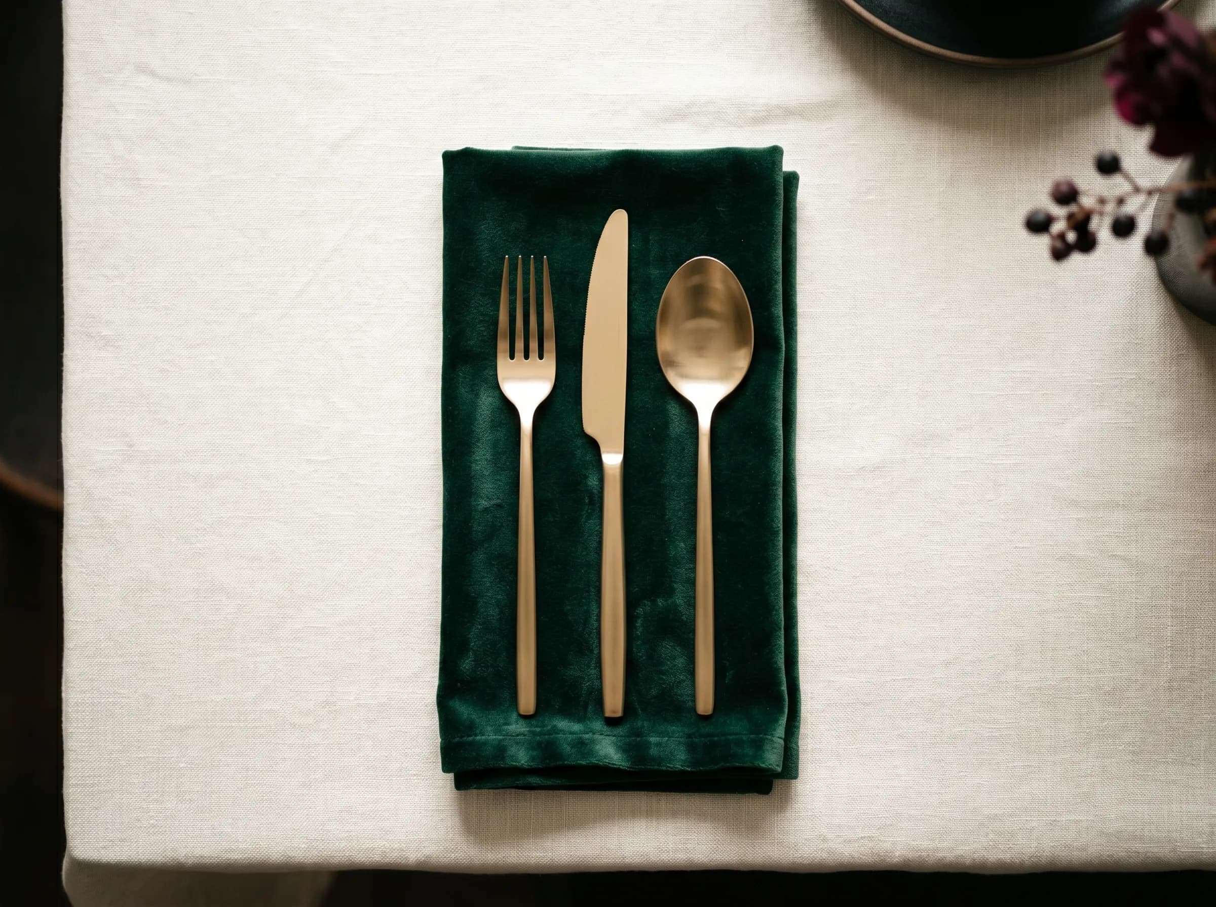 Gold-tone cutlery arranged on a folded emerald velvet napkin